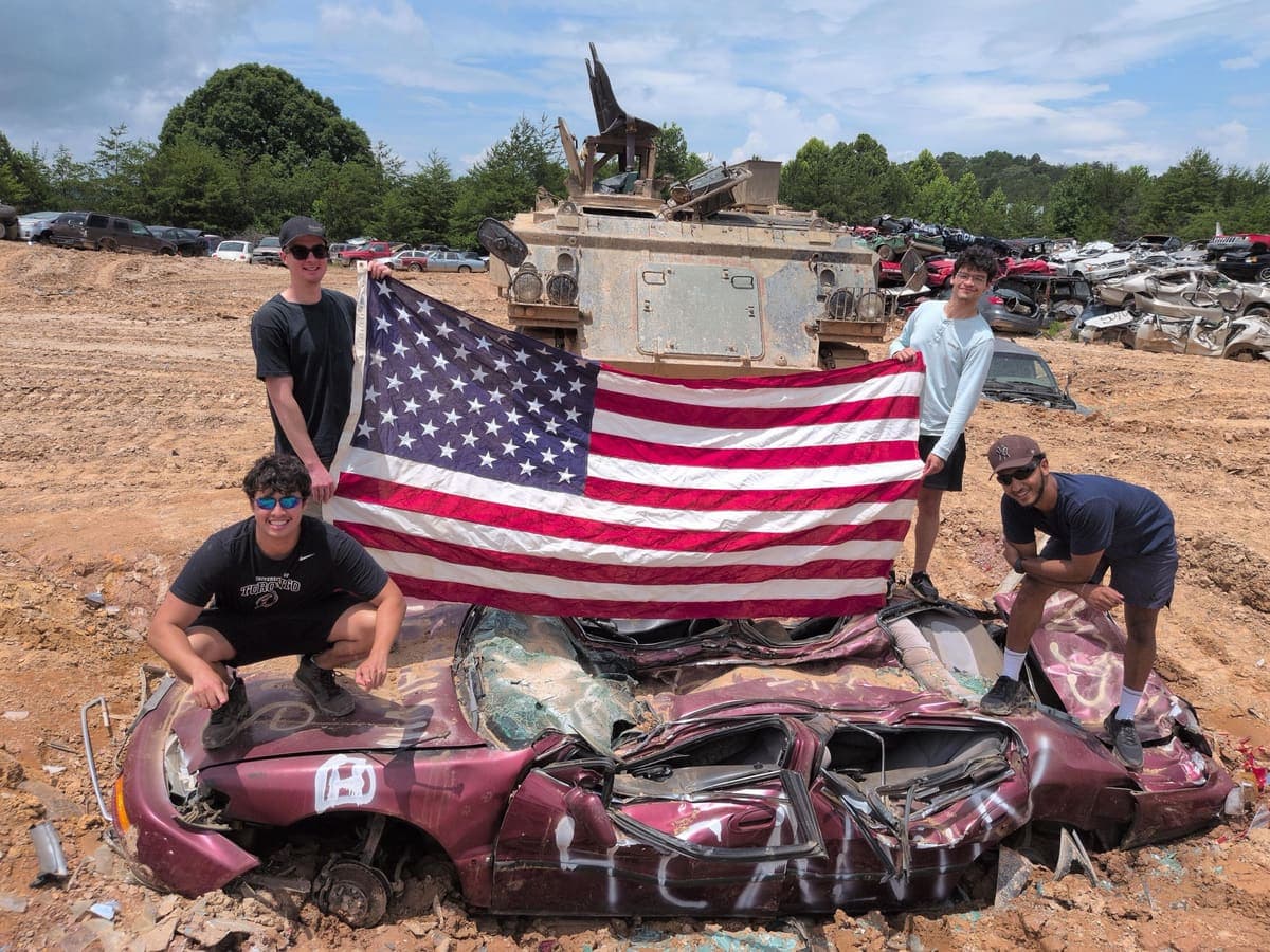 group holding US flag in front of tank